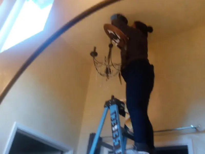 Electrician installing a chandelier in a Mission residence